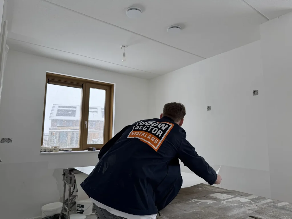 Behanger van Bouwsector Nederland pakt een baan van de plaktafel om die op de wand te zetten